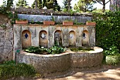 Alter Steinbrunnen mit Becken an Gartenmauer gesetzt (Villa Cimbrone)