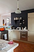 Offener Küchenbereich mit moderner Einbauküche, hellen Schrankfronten und teilweise schwarz getönter Wand
