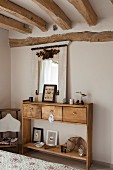 Solid-wood console table with drawers in rustic bedroom with wood-beamed ceiling