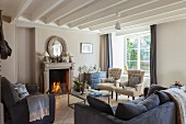 Open fireplace, classic upholstered furniture and exposed ceiling beams in living room