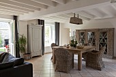 Wicker furniture in open-plan living-dining area of renovated farmhouse