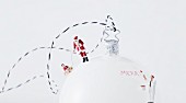White Christmas bauble decorated with miniature figurine of Father Christmas and other people