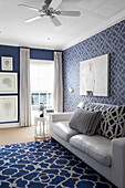 Living room with white leather sofa and blue patterned carpet