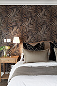 Bedroom with patterned wallpaper and wooden bedside table