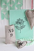 Hand-printed, heart-shaped linen cushions in front of mint-green canvas printed with floral motif