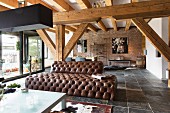 Brown leather sofa in loft-style interior with exposed, solid wooden beams