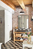 Bathroom with chequered floor, brick wall and washstand with trough-style sink on wooden frame