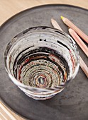 A birds-eye view of a homemade pencil pot made from folded strips of newspaper stuck together