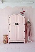 Pink-painted farmhouse wardrobe with black wrought iron fittings in pink interior