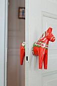 Door handle made from red-painted wooden horse
