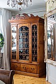Antique, carved wooden cabinet with glass door panels in traditional interior