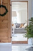 Christmas wreath on open wooden door with view of couch in living room