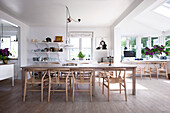 Designer chairs around long dining table in bright interior