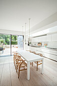 Designer chairs at white dining table next to long kitchen counter