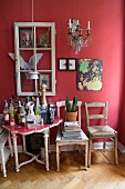 Drinks on antique table below window frame and decorative elements on red wall