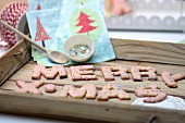 Alphabet biscuits with colourful sugar sprinkles spelling festive message on wooden tray