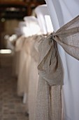 Sashes tied with bows on white, loose-covered chairs