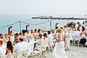 Wedding guests seated at long dining table by the sea