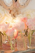 Delicate tulips in vases and jars on shelf and romantic mirror decorating feminine bathroom