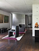 Room with dark wooden floor, modern art and exposed concrete walls an ceiling