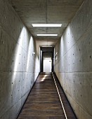 Corridor with sloping floor and concrete walls and ceiling