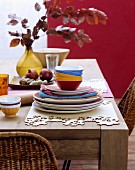 Colourful crockery and place mats hand-made from wooden veneer on rustic wooden table