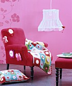 Pink interior with velvet armchair, footstool, crocheted accessories and vintage pendant lamp with fabric lampshade