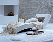 Teapot on tray on fur rug next to chaise longue next to fireplace