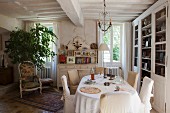 Oval dining table and loose-covered chairs in rustic, country-house dining room
