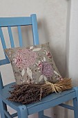 Bunch of dried lavender and embroidered cushions on blue-painted kitchen chair