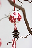 Polystyrene bauble festively decorated using napkin decoupage and with ribbon and pine cone