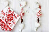 Festive arrangement of napkins, baubles, pine cones & love-hearts on wall