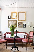 Symmetrically arranged gallery of pictures above antique upholstered furniture