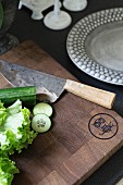 Chopping board engraved with owl, sharpened knife and vegetables