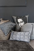 Various scatter cushions in shades of grey; plain, patterned and with picture of woman