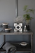 Various ornaments in shades of grey on side table against grey wall