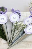 Hanging vases with letters on purple tags reading 'Noel' when put together