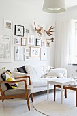 Fifty Sessel mit Holzgestell und Couchtisch-Set vor Sofa, Bildergalerie und Hirschgeweih an Wand