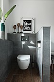 A separate toilet corner with a wall-mounted toilet on a grey-tiled wall