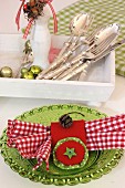 Hand-sewn, red napkin ring with pale green felt star and red and white gingham napkin on green glass plate