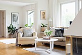 Armchair and round coffee table in living room in pale shades