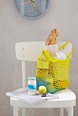 A homemade, yellow crocheted shopping bag on a white kitchen chair