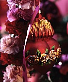 Red, heart-shaped Christmas tree bauble with rose motif on carnation wreath