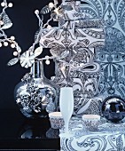 Christmas arrangement of crockery, vase, fairy lights & wrapped gifts in black and white