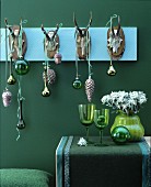 Christmas decorations in shades of green with baubles hanging from row of antlers