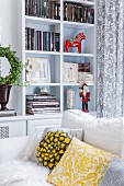 Red Advent horse figurine and nutcracker in white shelving compartments behind white sofa with yellow and grey scatter cushions