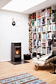 Log burner, floor-to-ceiling bookcases and reading armchair in cosy Scandinavian living area