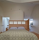 Schlafzimmer im Dachgeschoss mit weißem Einbauschrank und Bad Ensuite im Designerstil, organische Deckengestaltung und maßgeschreinerter Raumteiler als Bettkopfteil