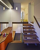 Designer staircase with glass balustrade, exotic-wood treads, view into corridor and orange wall with wooden top