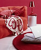 Loose-covered sofa with cosy blankets and scatter cushions in red and white interior; laptop on grey cushion on floor